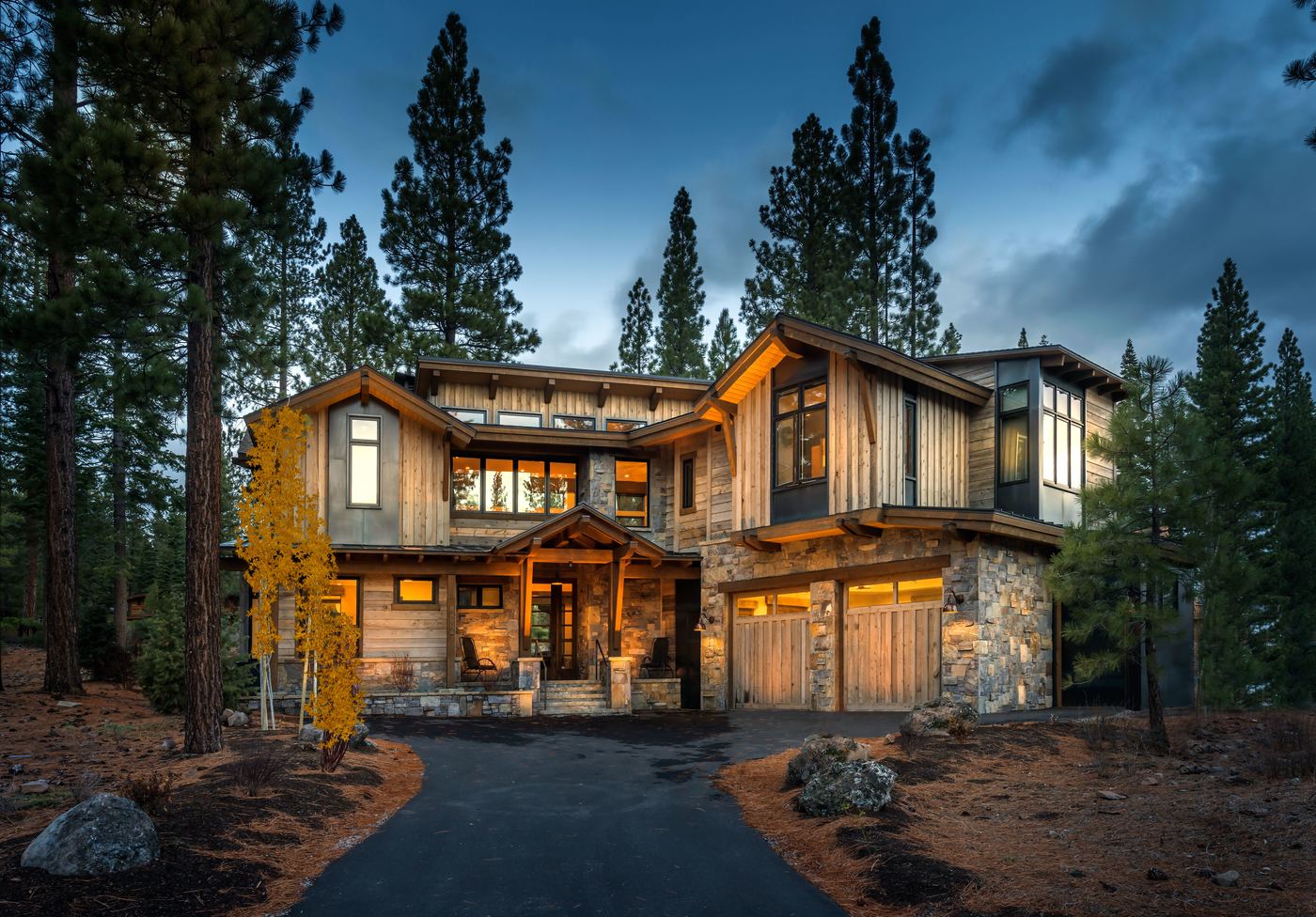 Timber and glass residence lit from within among pines