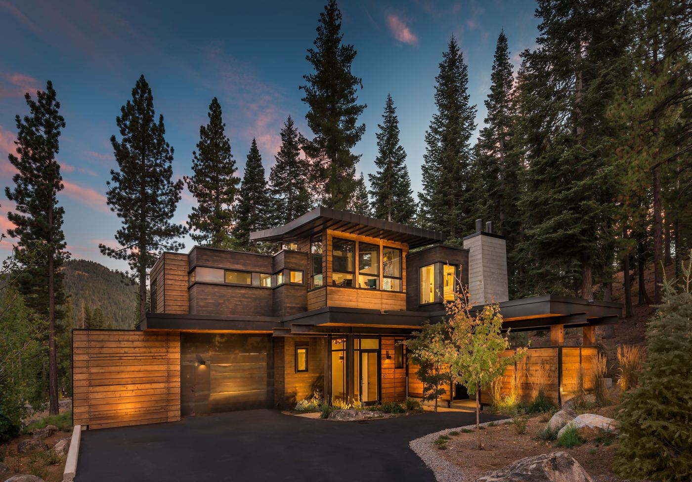 Modern mountain residence lit from within at dusk