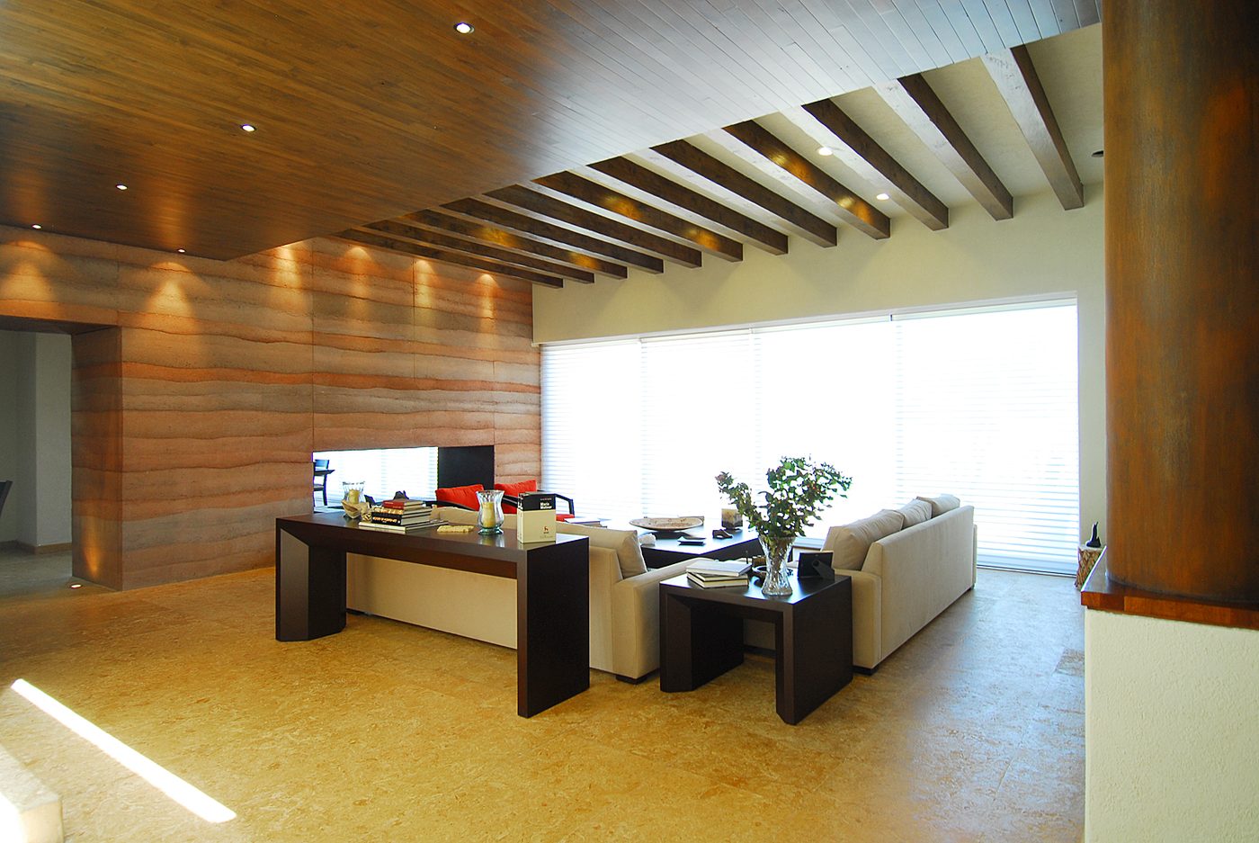 Second interior with the rammed-earth wall, corten column and stone floor