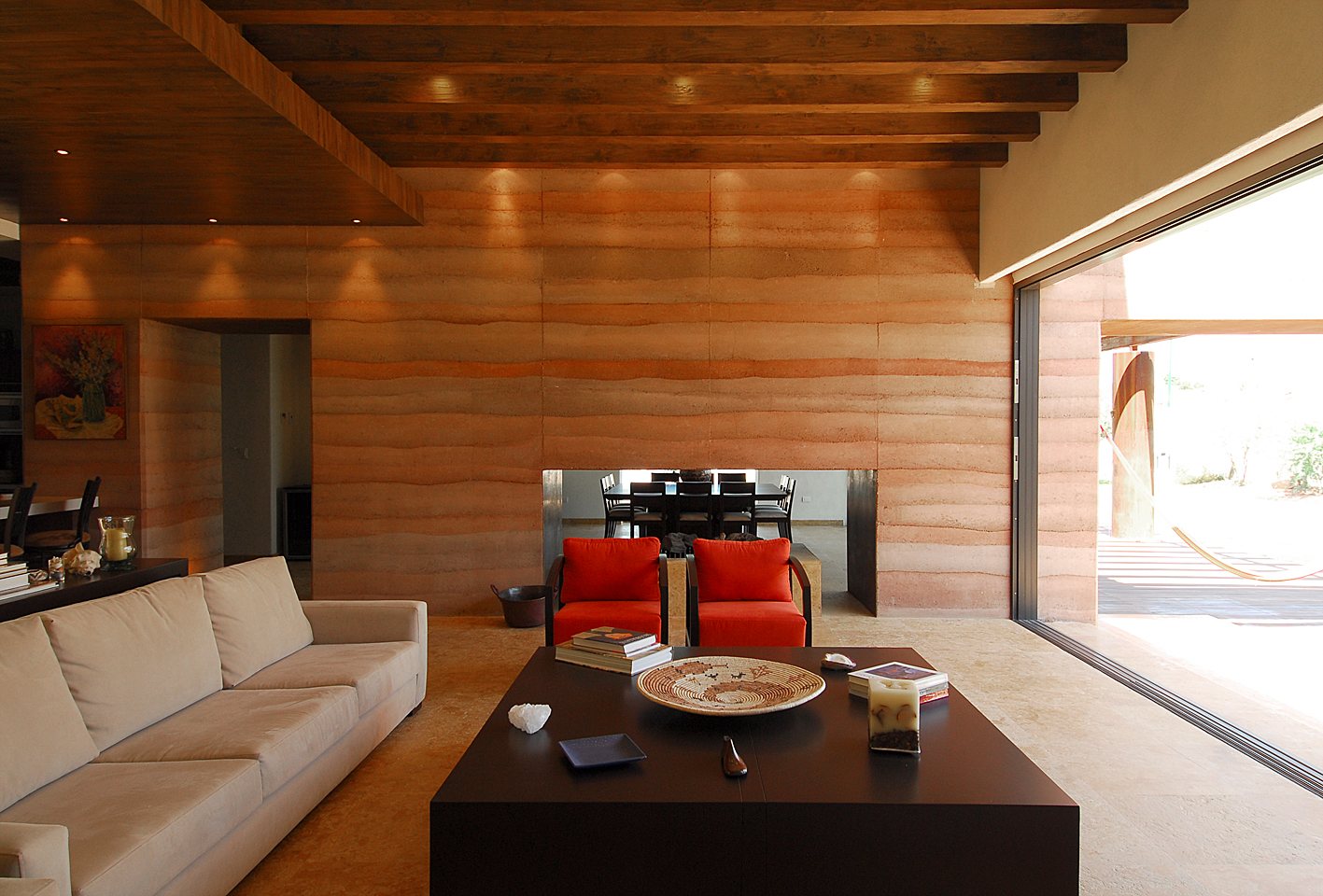 Adobe Residence: a long rammed-earth wall with its lifts visible, a tree in the lawn and the white volumes behind