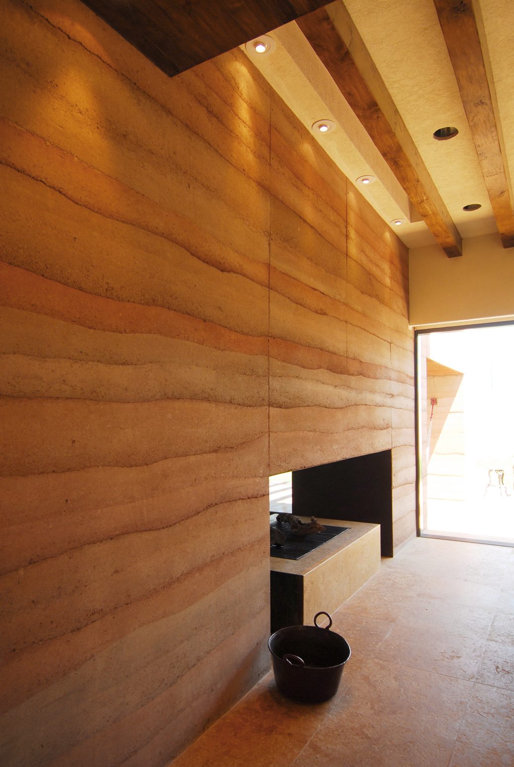 Close view of the rammed-earth wall, its lifts running across the frame