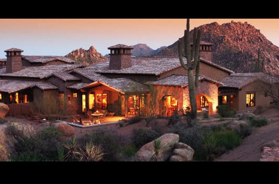 The Rocks at dusk: low tile-roofed villas with a chimney tower, boulders in the foreground and the rock peak behind