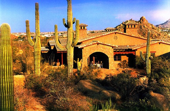 The villas seen through a stand of saguaros, with the rock outcrop behind