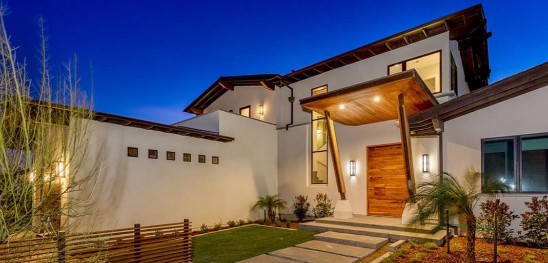 Entry at dusk: timber door under a deep canopy carried on angled brackets