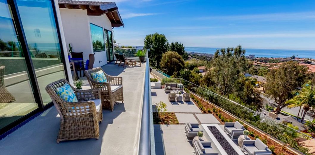 Upper terrace with lounge seating, glass rail and the ocean on the horizon