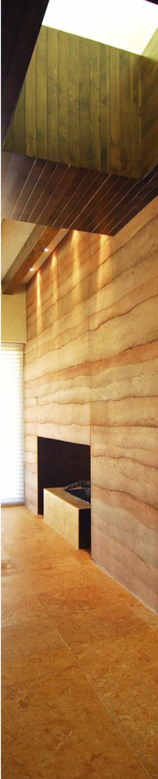 Rammed-earth wall inside a house, the layers of each pour lit from above